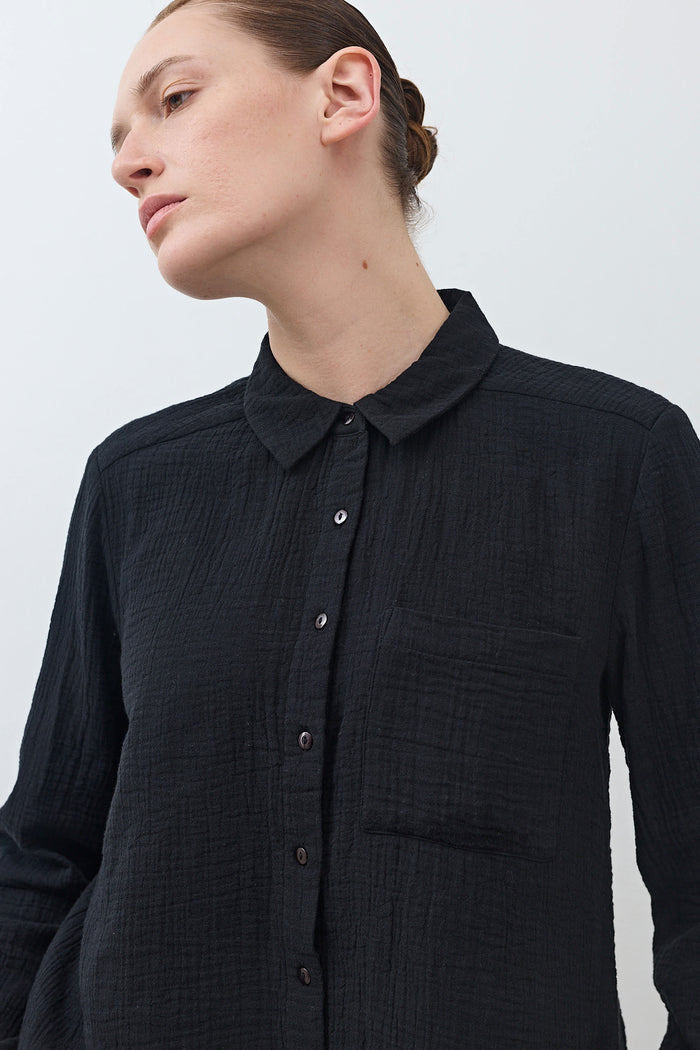 Black button-down tunic with pointed collar and front button placket, long sleeves