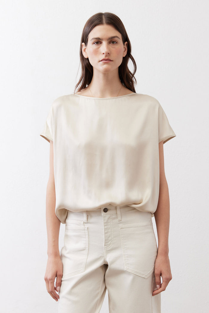 Light cream silk blouse with crew neck, short sleeves, and elasticized hem