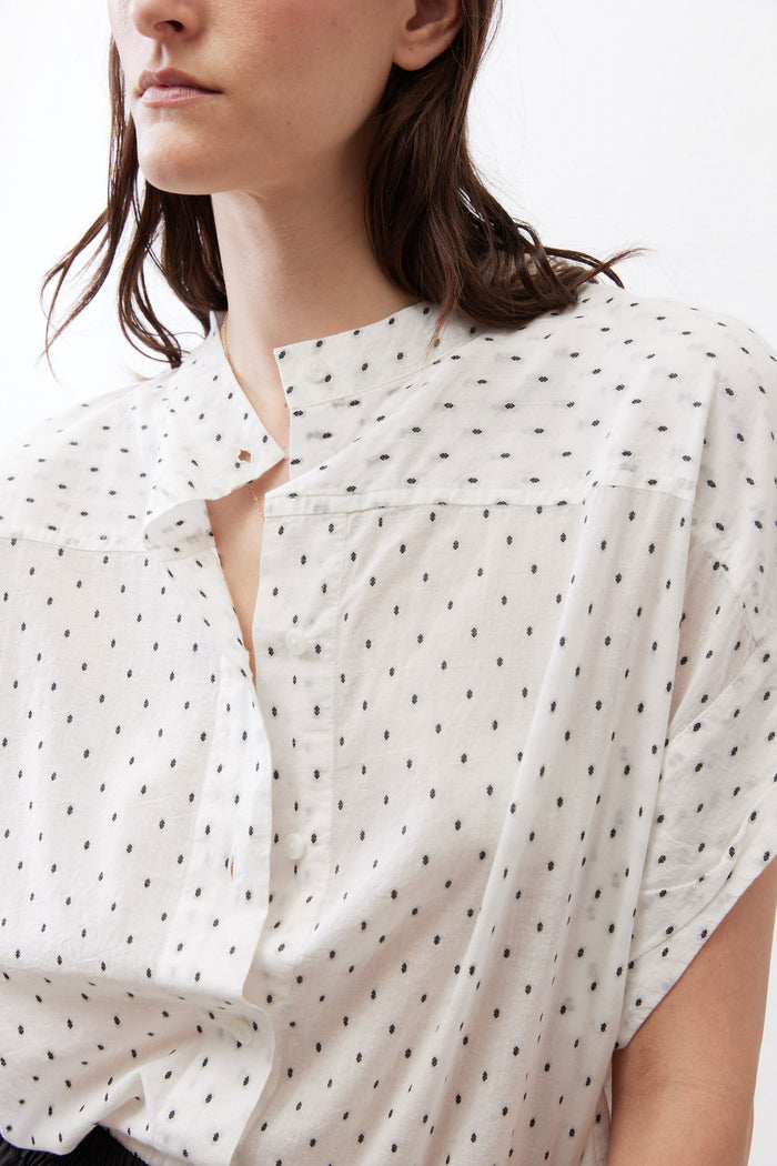 White blouse with black dot print, close-up of V-neck button placket