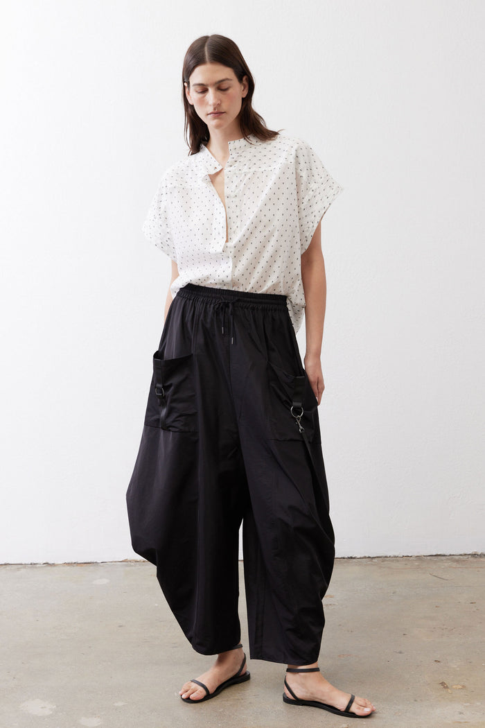 Black parachute wide-leg pants with elastic waist, tie cords, and pocket hardware.