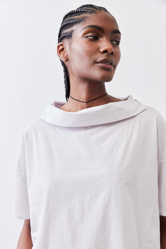 White dolman drape-neck top neckline detail with draped cowl hood