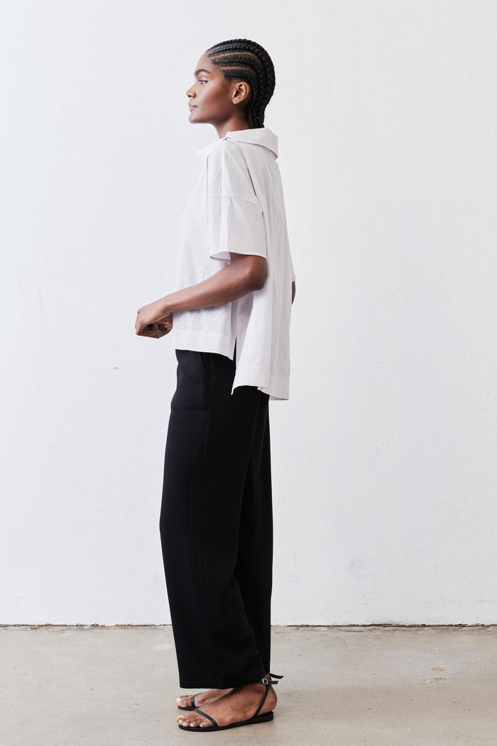 White dolman drape-neck top, side view with short sleeves and draped neckline