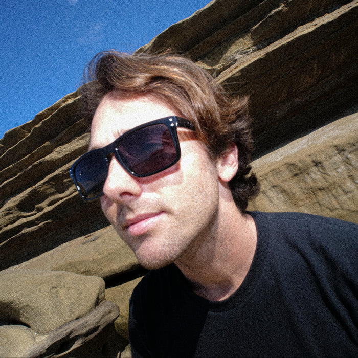 Man wearing sunglasses with a rocky landscape in the background