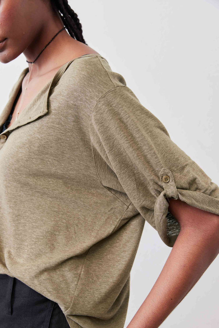 Warm olive elbow-sleeve top detail with half-button placket and sleeve cuff