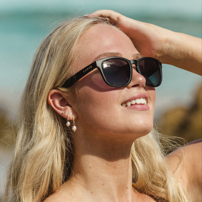 Woman wearing sunglasses with a blurred beach background