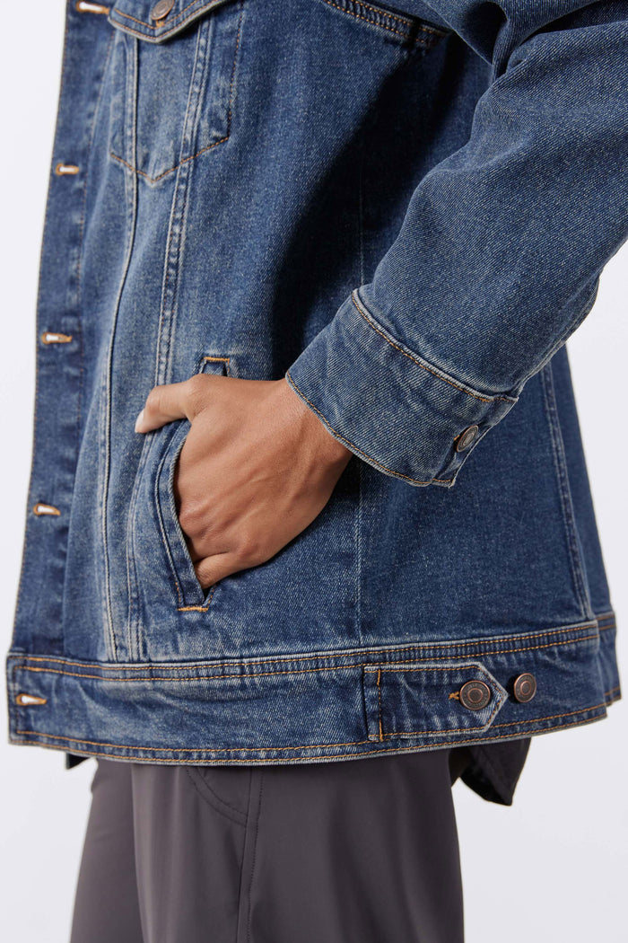 Long line denim jacket hem detail, medium-wash blue with button closure and flap pocket.