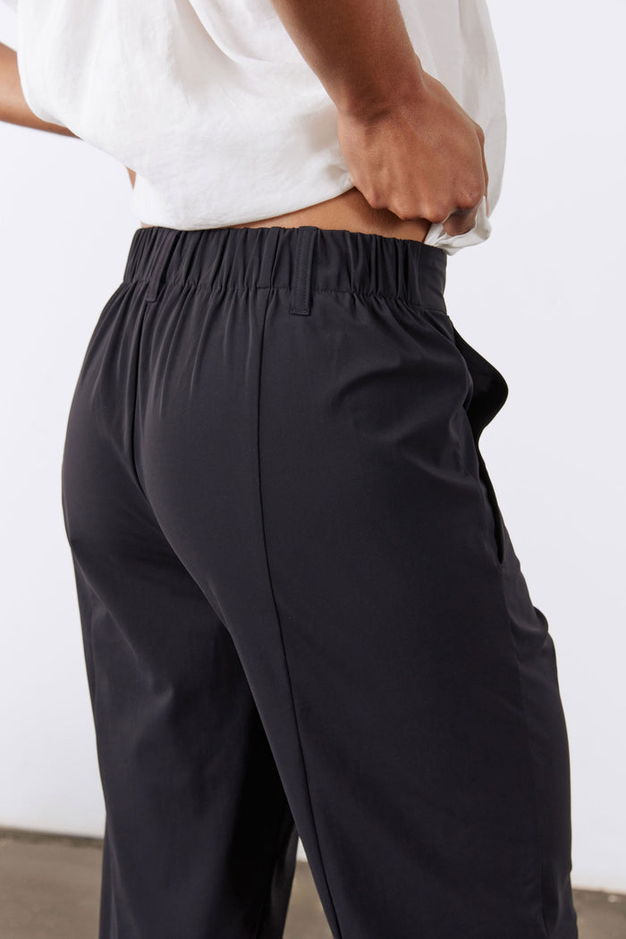 Black pull-on tapered pants with elastic waistband and front pleat lines.
