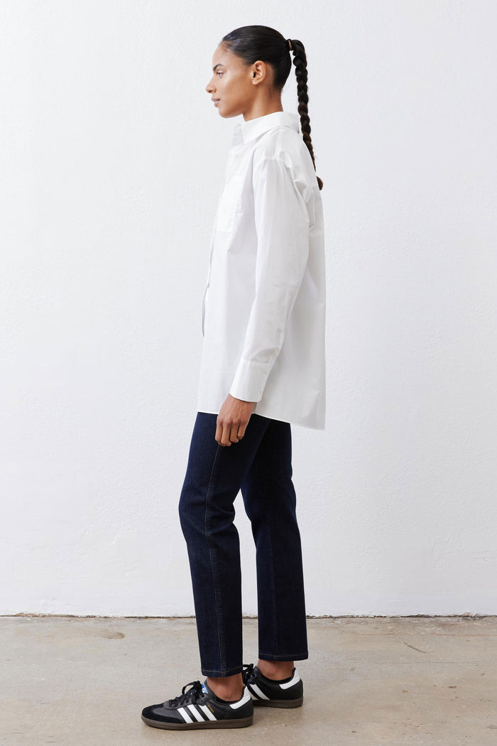 White asymmetric button-down shirt, long sleeves and pointed collar, side profile