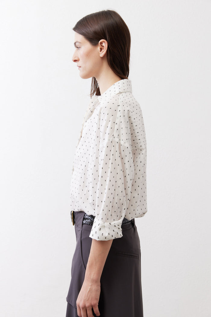 Side view of white oversized tunic with black dot print, collared button placket