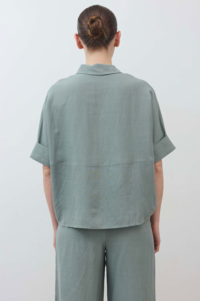 Back of oversized Chinois green blouse with short sleeves and relaxed shoulder