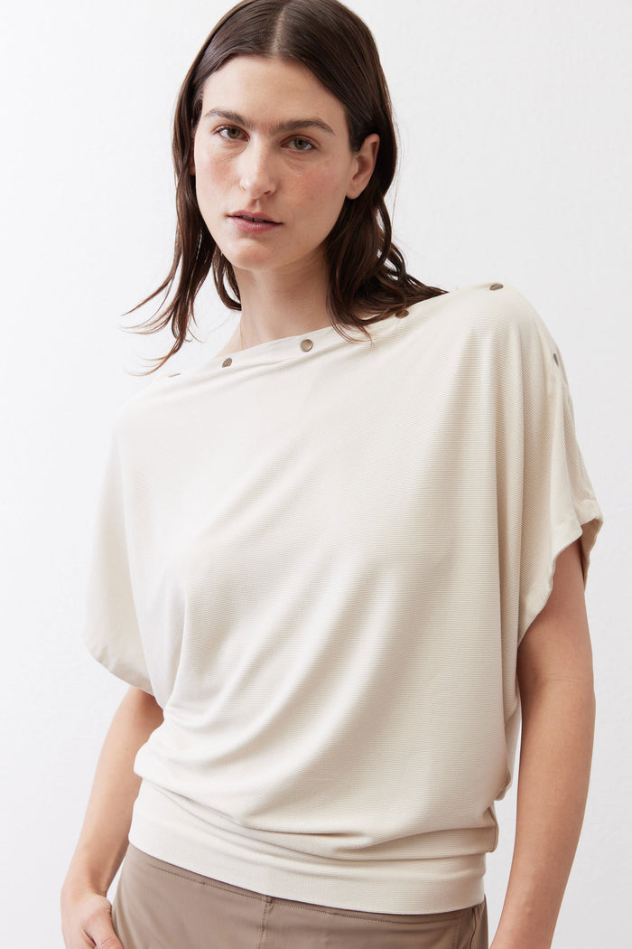 Cream short sleeve top close-up with round neckline and shoulder buttons