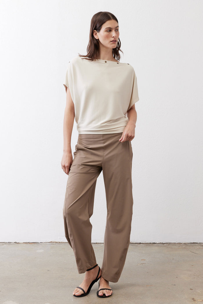 Cream short sleeve top three-quarter view with round neckline and shoulder buttons