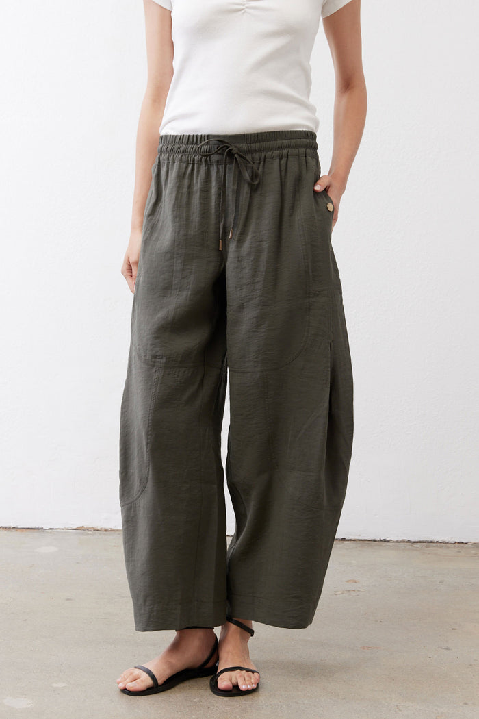 Baggy utility pants in dark olive with elastic waistband and drawstring, relaxed wide silhouette.