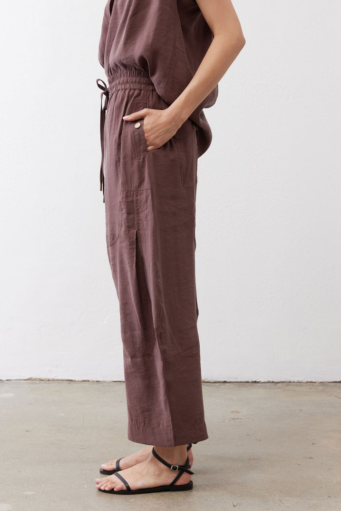 Dark brown utility pants detail: cropped side view with drawstring and seam pockets