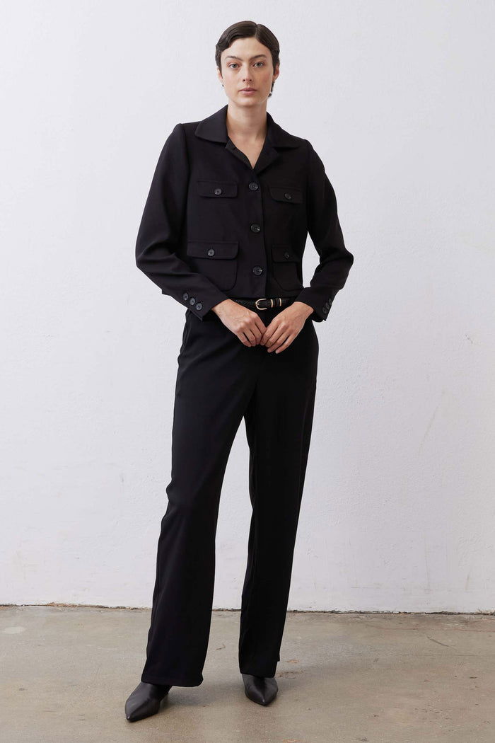 Black collared classic jacket with button front, flap pockets, long sleeves, and belt