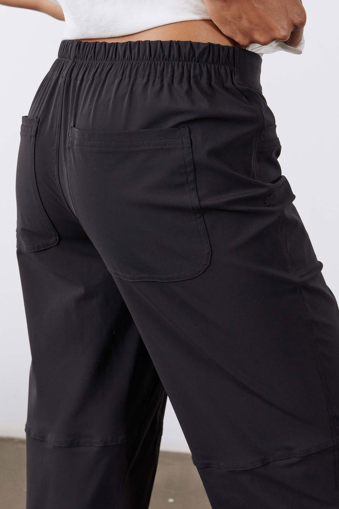 Black slim pants with elastic waistband and front pockets, side view.