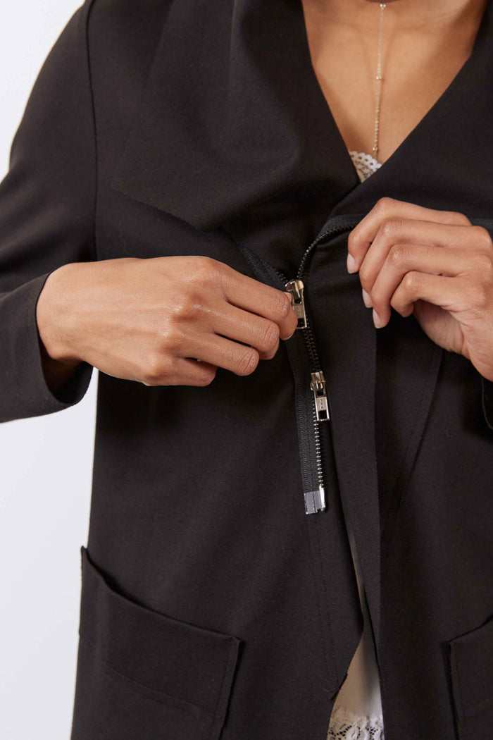 Black jacket showing zipper pull and hands closing the front