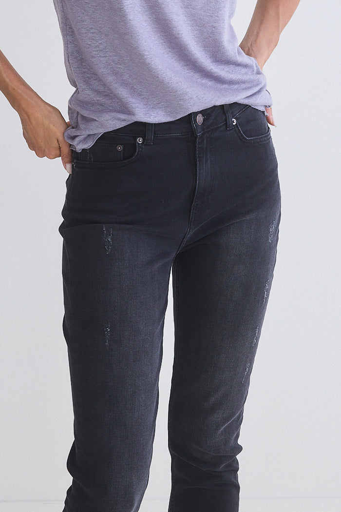 Dark jeans close-up with front button, pocket, and subtle wash effect