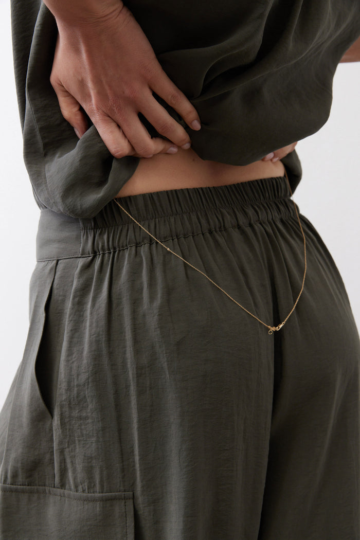 Dark green skirt-style pants with elastic waist and front cargo patch pockets