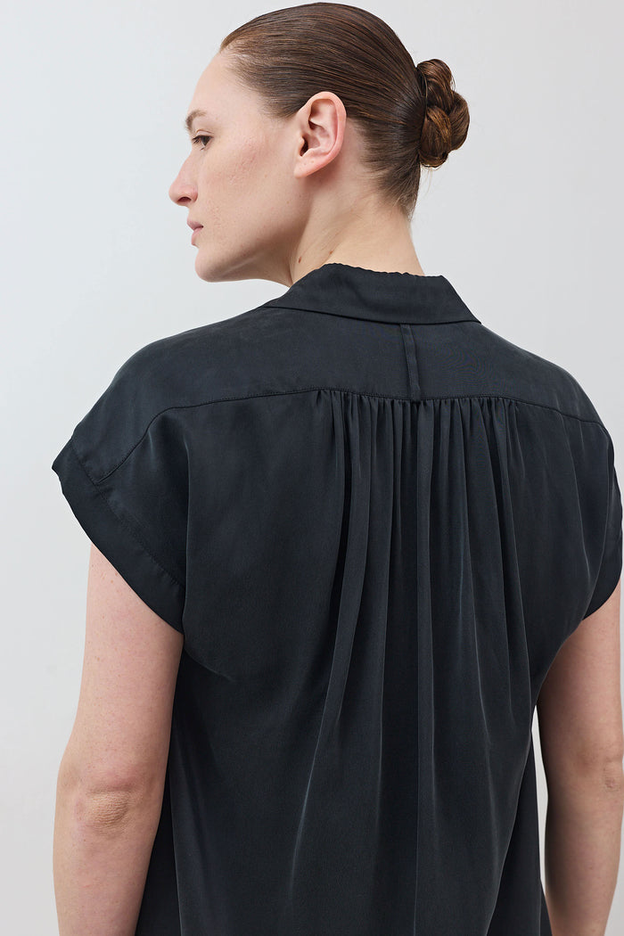 Back of black oversized silk blouse with pleated yoke and gathered shoulders