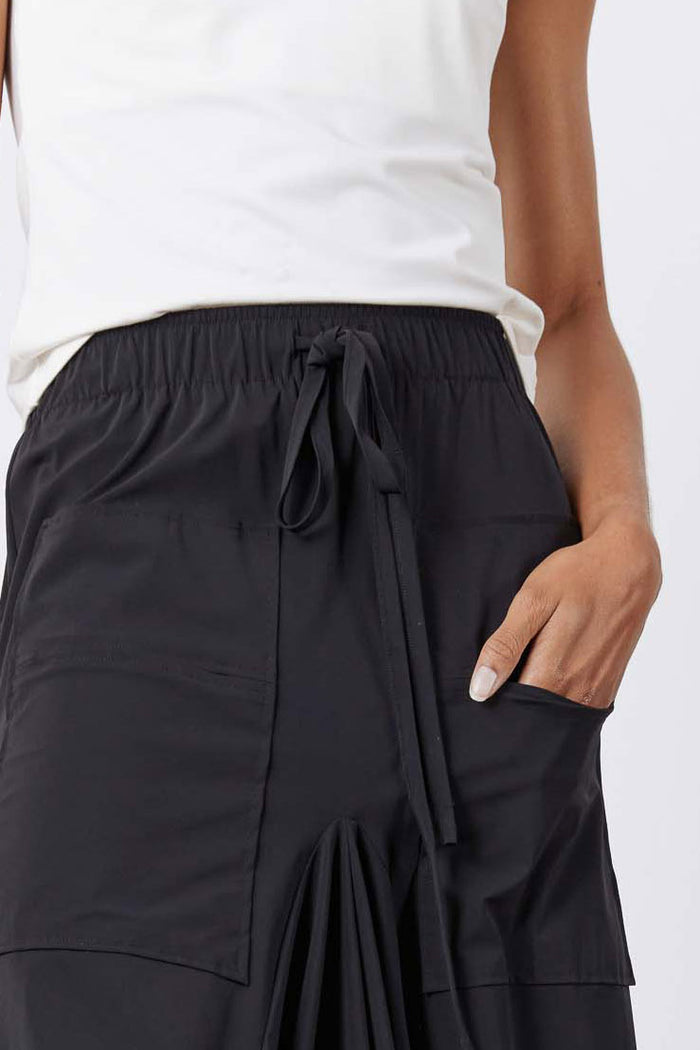 Black skirt detail: drawstring waist, front pocket panel, and gathered drape folds