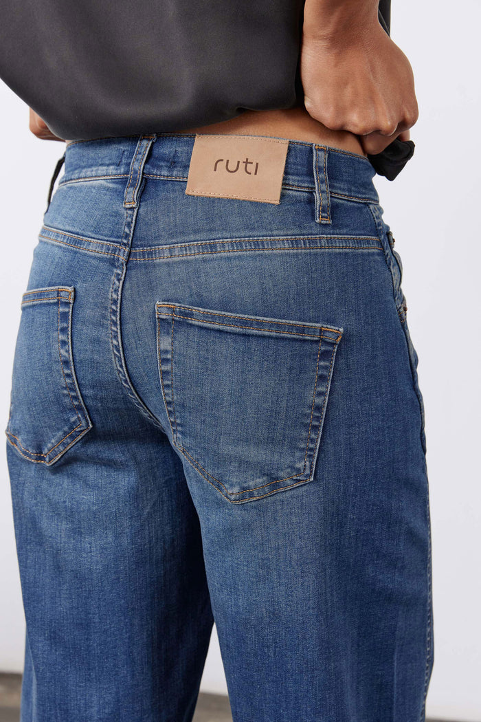 Indigo barrel-leg jeans with tan 'ruti' waistband patch and button closure
