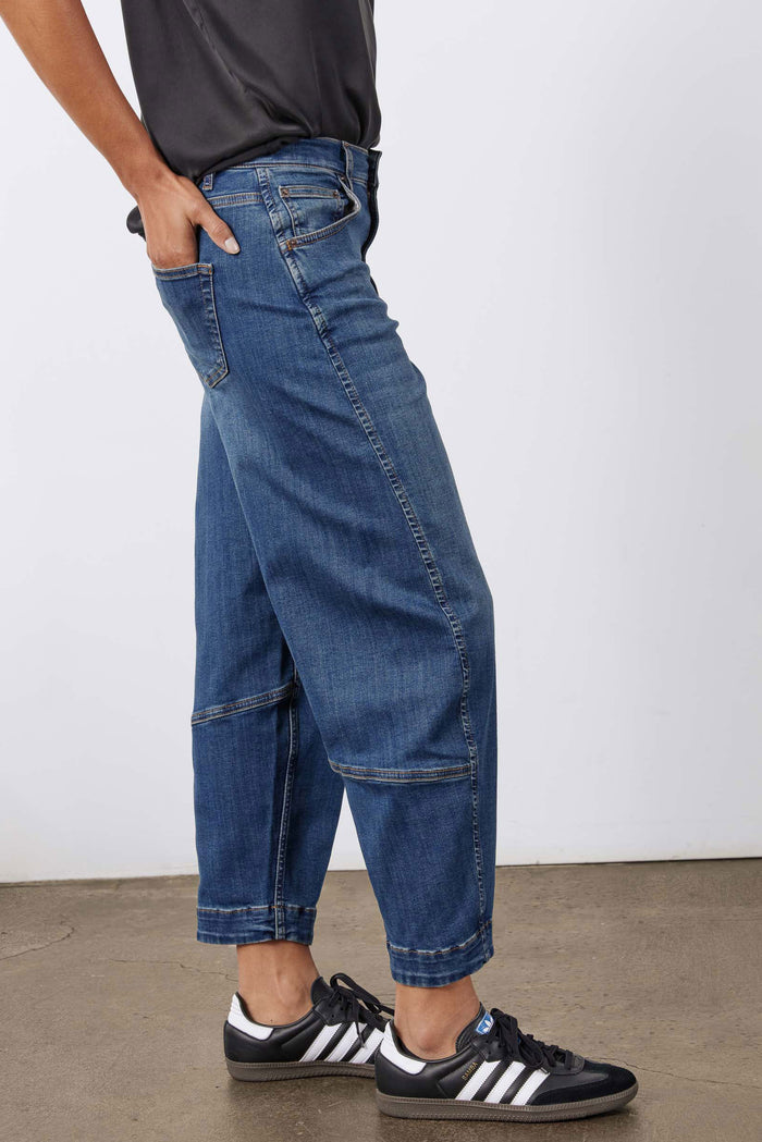 Indigo barrel-leg jeans with stitched seams, cuffed ankle hem, and side pockets