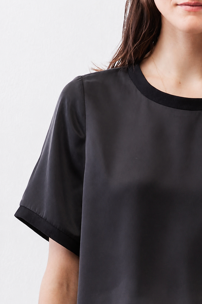 Black crew-neck silk top with short cuffed sleeves detail