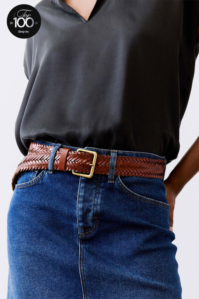 Brown leather woven belt with brass buckle on blue jeans with black top