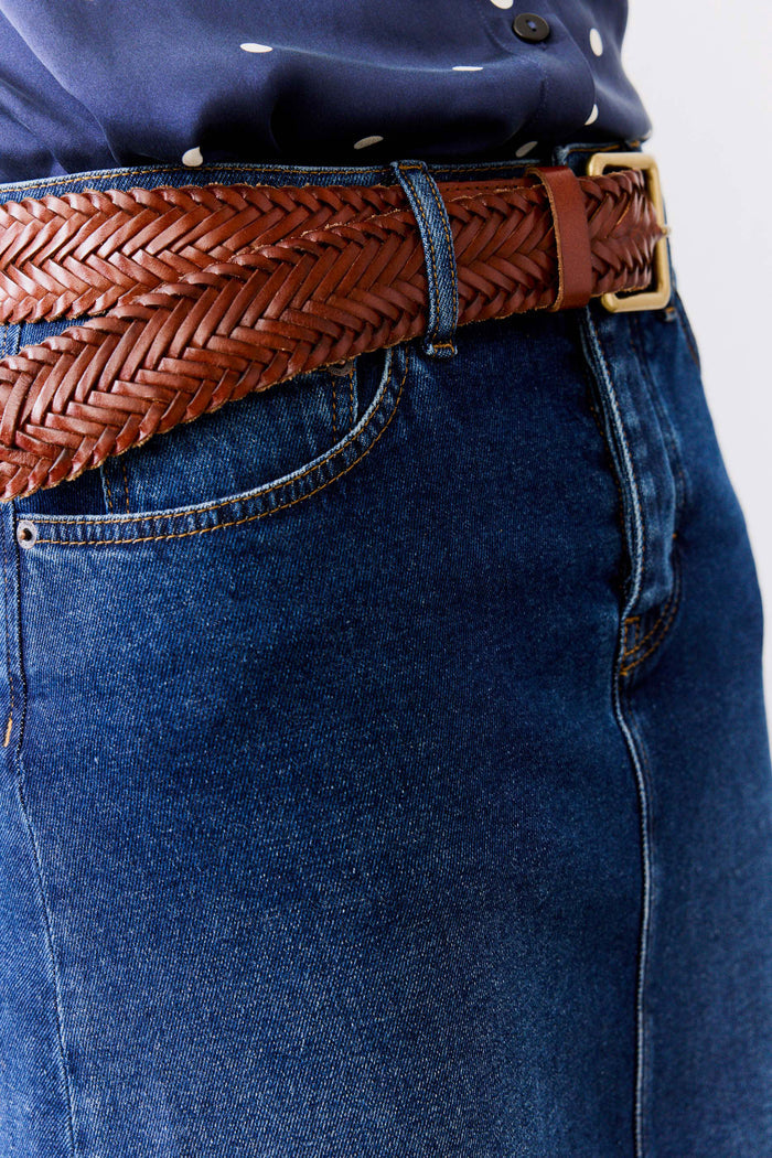 Woven brown leather belt detail with brass buckle and denim jeans