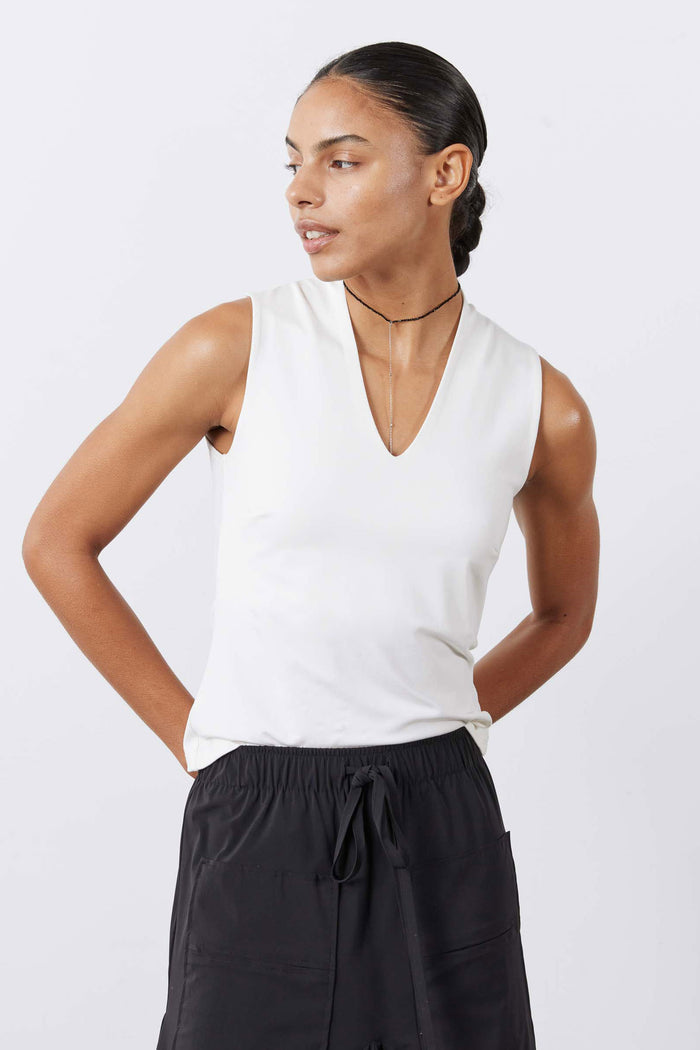 White V-neck sleeveless tank top with sculpted fit, worn with black drawstring pants.