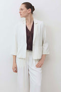 White shrunken blazer with structured shoulders, notch lapel, and 3/4 sleeves.
