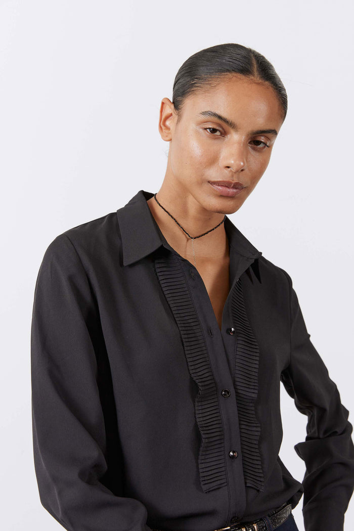 Black button-up blouse with point collar and ribbed front placket, close chest view