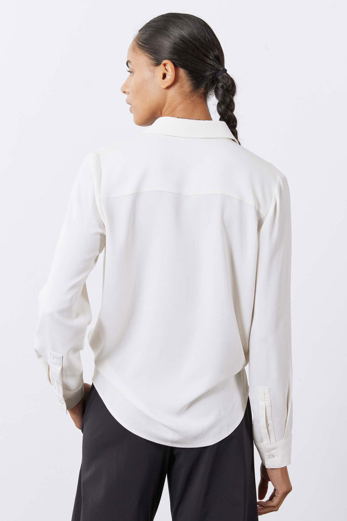 Back view of off-white button-up blouse with pointed collar and long sleeves