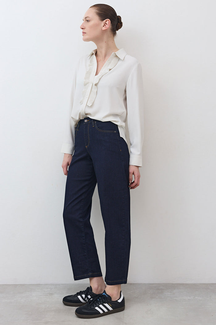 Side view of off-white blouse with pointed collar, button front, and pleated trim detail