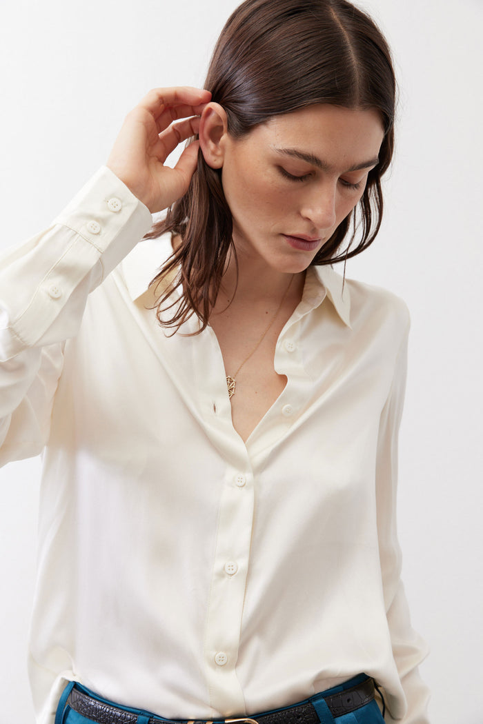 Ivory silk button-down top close-up with long sleeve cuff and button front