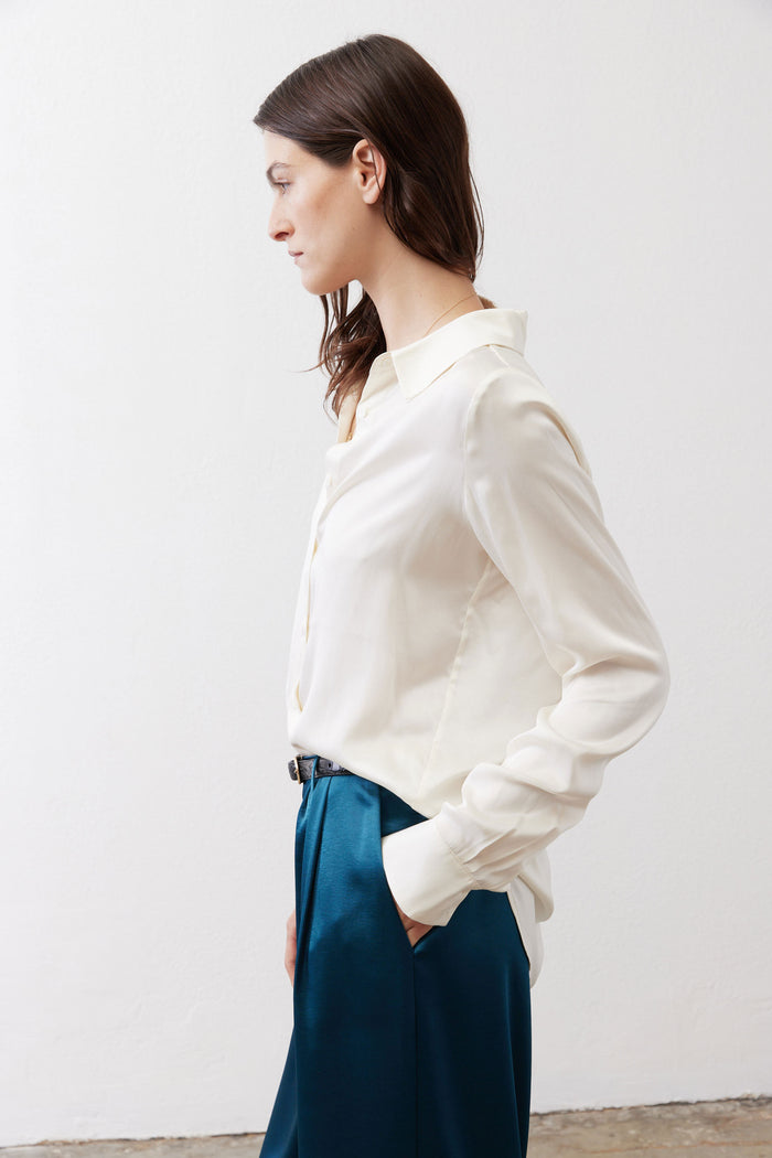 Ivory silk button-down top in side profile with buttoned cuffs