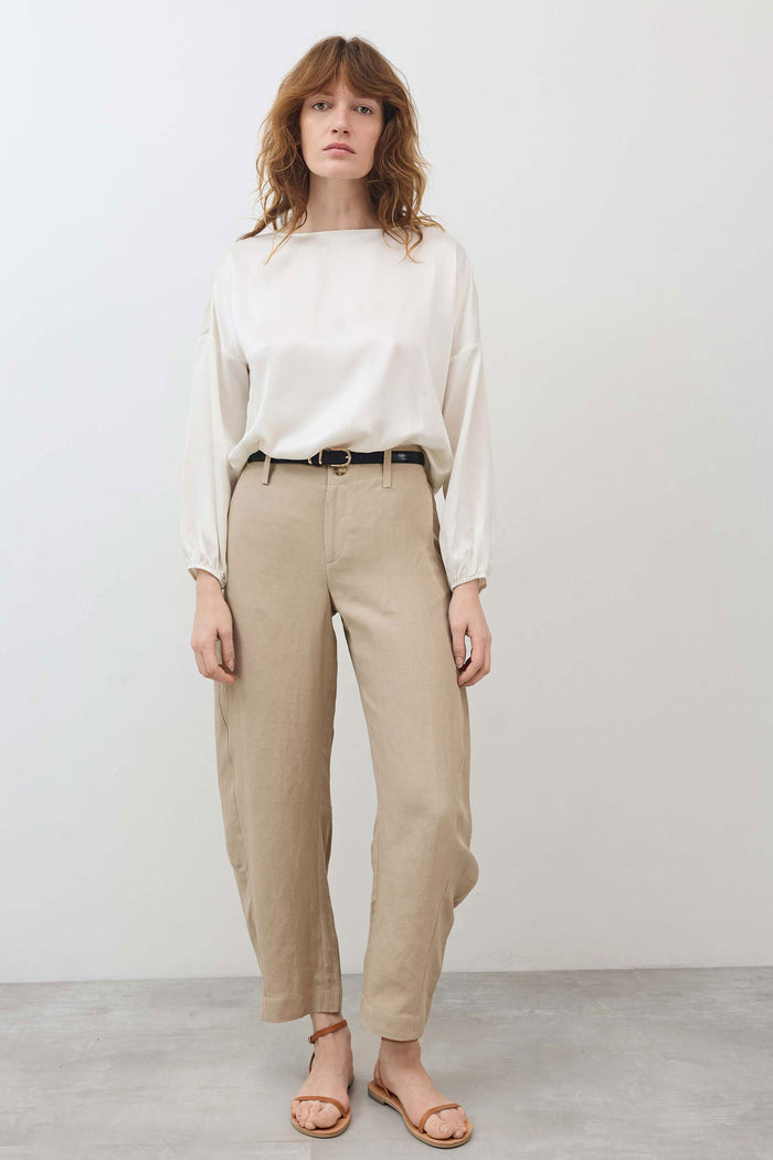 Ivory silk blouse with scoop neck and billowy sleeves, cinched hem at waistline